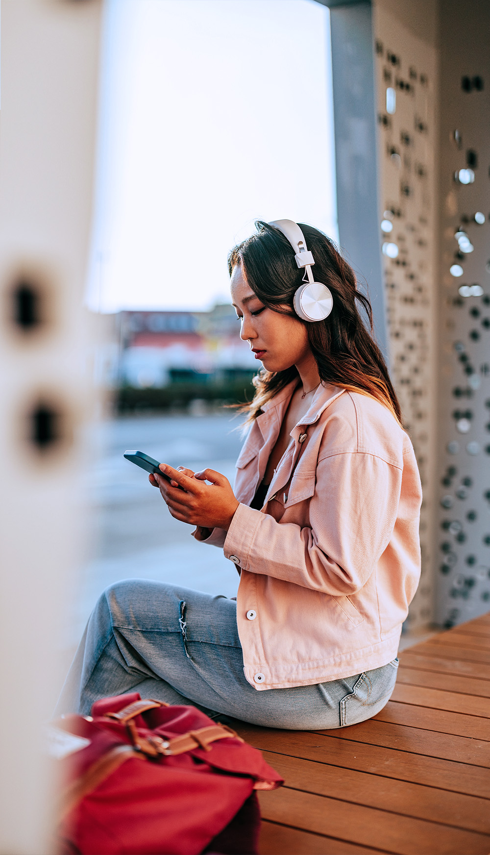 Young woman in public listening to music on a smartphone